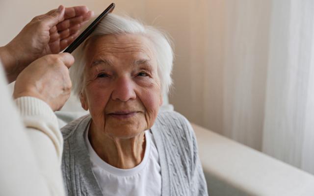 Cuidadora peinando a una mujer mayor.