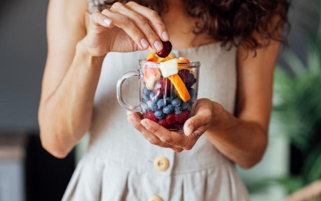 Mujer tomando frutas recomendadas para diabéticos.