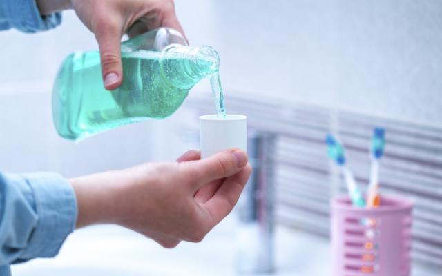 Persona utilizando enjuague bucal