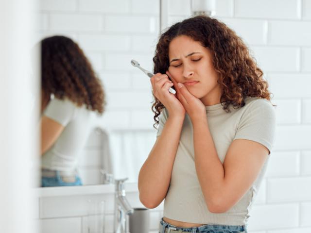 Chica con dolor de muelas por no saber cómo prevenir las caries. 