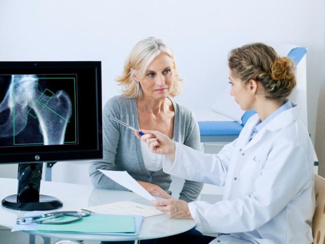 Médico explicando a paciente cómo prevenir la osteoporosis. 