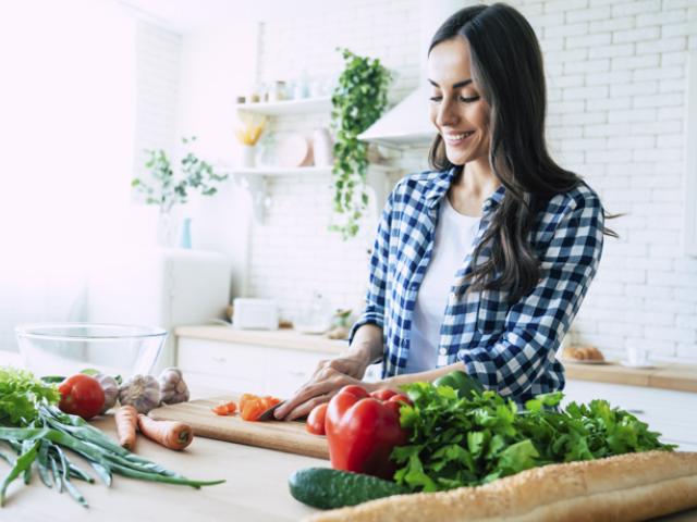 Mujer prepara comida con alimentos anticancerígenos